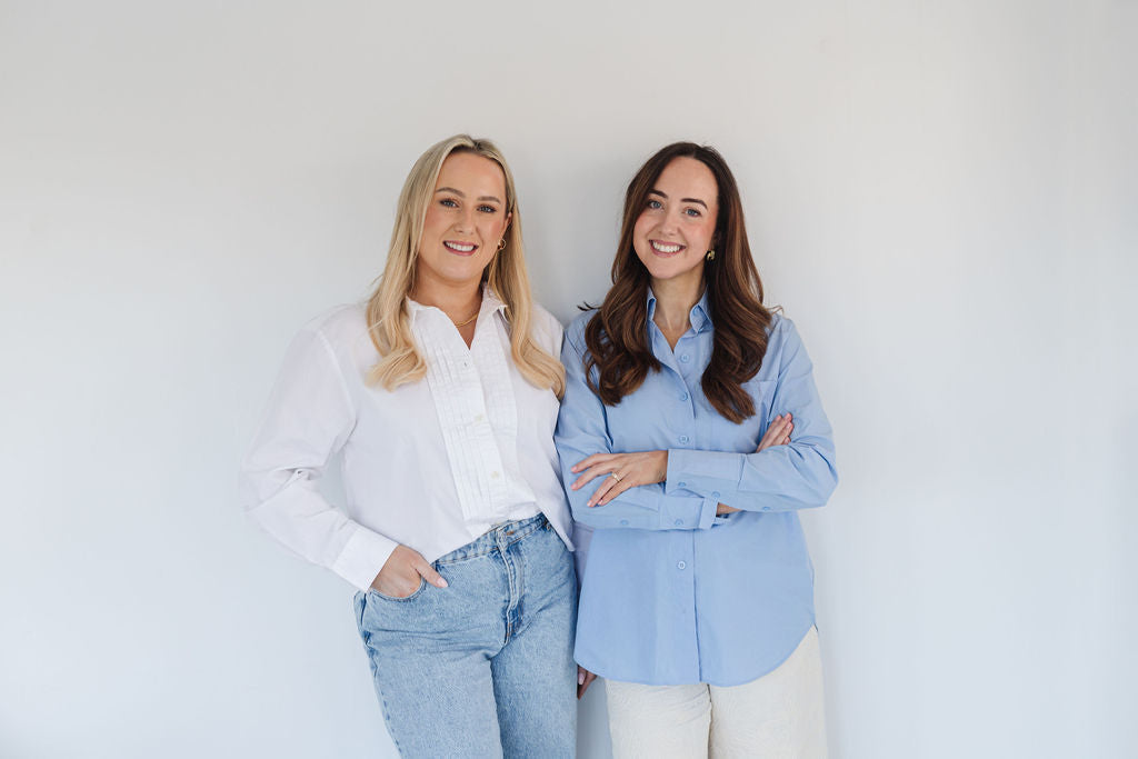 Gigi founders Jennie Haire and Lisa Hughes standing together against a white wall